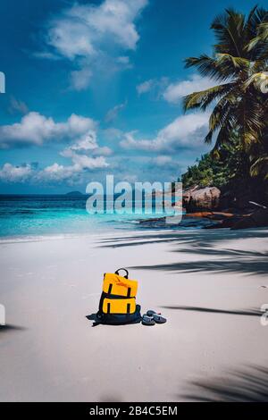 Traveler gelben Rucksack und Flip Flops auf dem sandigen tropischen Strand im Sommer Urlaub Reise, Reisen Hintergrund mit kopieren. Stockfoto