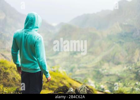 Tourist in Hoodie vor ländlicher Landschaft mit Bergen, auf dem Weg ins Paul-Tal. Insel Santo Antao, Kap Verde. Stockfoto