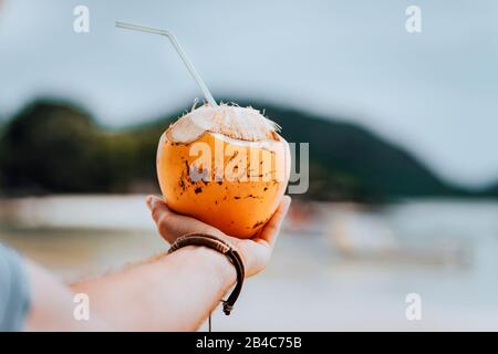 Halten Sie einen tropischen Cocktail in einer Kokosnuss an einem wunderschönen Strand auf der Insel Mahe. Stockfoto