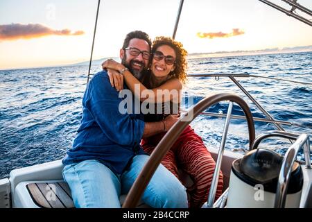 Glückliche Menschen kaukasische Erwachsene Paare genießen die Segelbootfahrt im Sommerurlaub - Freizeitaktivität im Freien mit Meer und Sonnenuntergang im Hintergrund - Segeln mit Liebe und Romantik Stockfoto