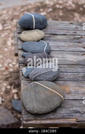 Anordnung von Kieselsteinen mit weißer Linie auf dem alten Holzsteg am Strand Stockfoto