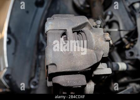 Bremsscheiben vorne mit Bremssattel und Bremsbelägen im Auto, auf einer Hebebühne in einer Werkstatt. Stockfoto