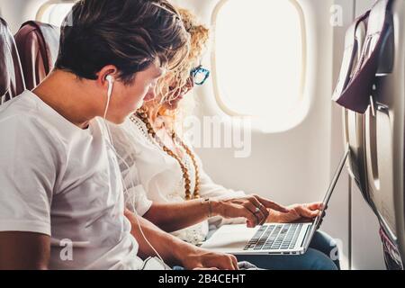 Glückliche Reisende Paare Mutter und Sohn setzen sich im Flugzeug ab, um den Flug mit einem PC-Laptop mit Internetverbindung an Bord zu genießen - moderne Technologie und Reisepersonalkonzept Stockfoto