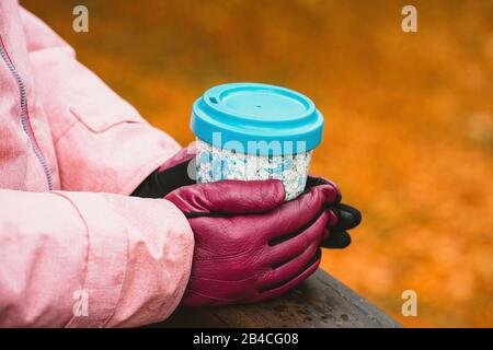 Hände in Handschuhen halten einen Becher Stockfoto