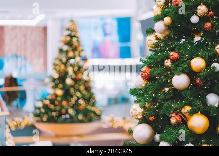 Weihnachtsbäume mit roter und goldener Dekoration im Einkaufszentrum. Stockfoto