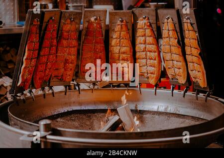 Lachsfische rauchten auf dem Weihnachtsmarkt in Hamburg im offenen Feuer. Stockfoto