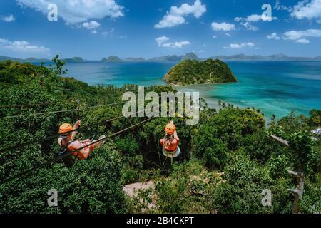 Zipline über Las Cabanas Strand mit Touristen am sonnigen Tag mit weißen Wolken über dem Meer. El Nido, Palawan, Philippinen. Stockfoto