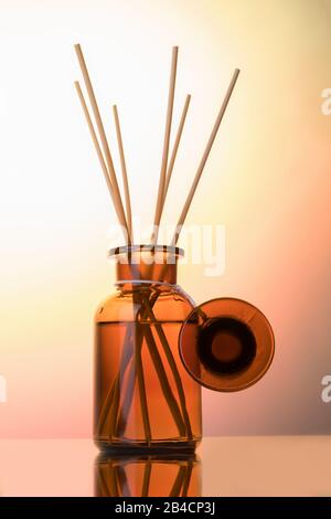 Lufterfrischungsflasche verspottete, Schilfdiffusor auf einem hellen Rosenstimmer-Hintergrund. Aromatherapie-Konzept. Hausduft-Flasche Stockfoto