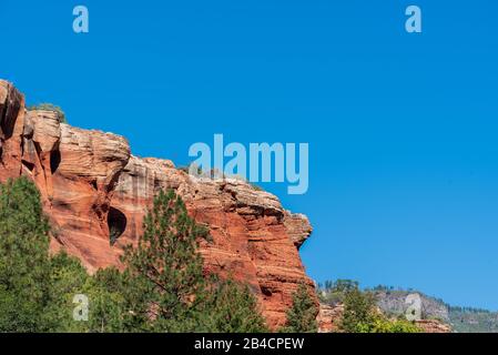 Grüne Landschaft im unteren Winkel auf roten, weißen und orangefarbenen Felshängen im Slide Rock State Park in Sedona, Arizona Stockfoto