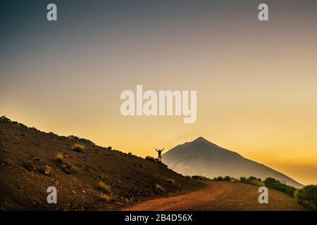 Konzept von Erfolg und Freiheit mit Glück - stehender Mann mit hochstehenden Armen, der im Hintergrund den Blick auf einen Bergvulkan genießt - Trekking- und Abenteuerurlaub für Menschen Stockfoto