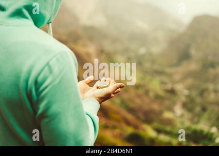 Insel Santo Antao. Kap Verde.. Man-Entdecker, der Kompass vor entschärftem bergigem Gelände im Hintergrund hält. Stockfoto