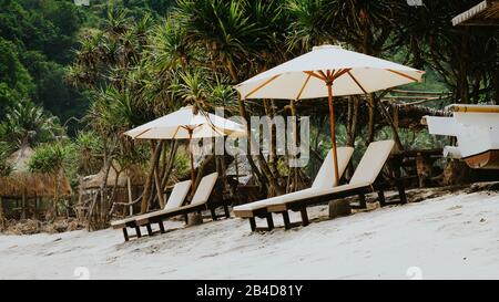 Sonnenbank auf weißem Sand unter Palms am Atuh Beach, Nusa Penida, Bali, Indonesien Stockfoto