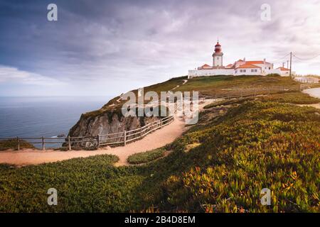 Reisen Sie in die Region Portugal Sintra. Blick auf das helle Haus in Cabo da Roca oder Cape Roca in Sonnenschein und niedrigen Wolken. Stockfoto