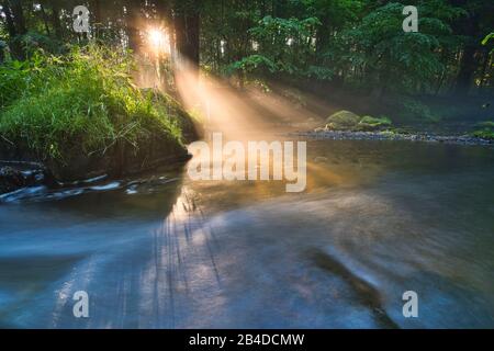 Sonnenauf- und Nebelfäden über dem Wasser eines Flusses Stockfoto