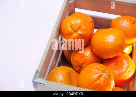 Viele Mandarinen in einer Holzkiste auf pinkfarbenem Grund Stockfoto