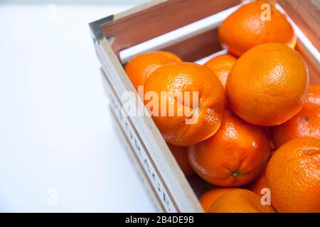 Viele Mandarinen in einer Holzkiste auf pinkfarbenem Grund Stockfoto