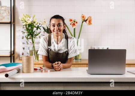 Schöne Frau Floristin steht an der Theke im Blumenladen und schaut auf die Kamera Stockfoto