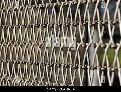 Eine Nahansicht der Metallverbindungen eines Kettengliederzauns macht ein attraktives abstraktes Muster. Stockfoto