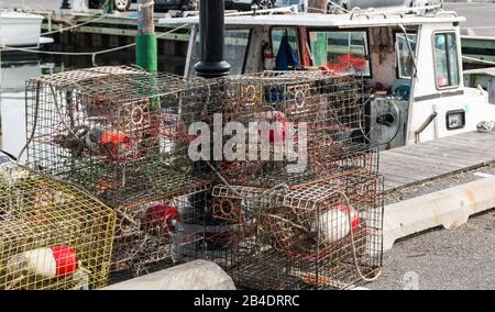 An den Docks sitzen Krabbenfallen auf dem Boden, die bereit sind, mit Ködern gefüllt zu werden und wieder ins Wasser zu legen. Stockfoto