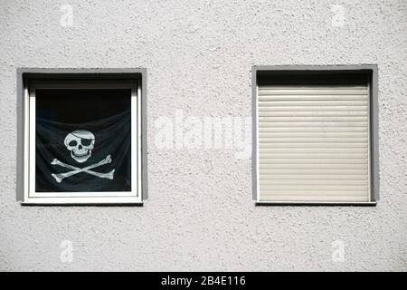 Eine schwarze Piratenflagge mit Totenkopf im Fenster. Stockfoto