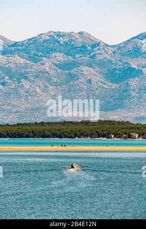 Ein Boot auf dem Meer in der Nin Bay. Im Hintergrund der Berg Velebit in Kroatien. Stockfoto