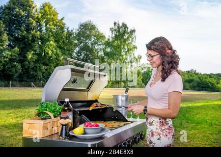 Junge Frau grillte im Garten, Grill Stockfoto