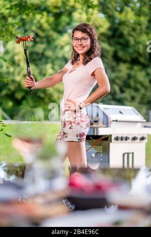 Junge Frau grillen im Garten, Grill, posen Stockfoto
