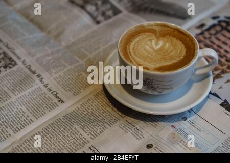 Latte mit Herz- und Zeitungsbruch Stockfoto