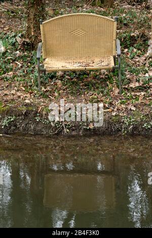 Alte Bank am Ufer eines Stroms entsorgt. Stockfoto