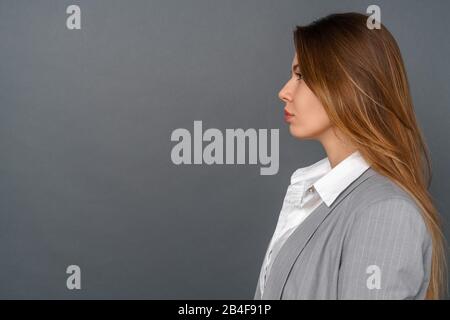 Studio für junge Geschäftsfrauen isoliert an der grauen Wand mit Blick auf die Seitenansicht Stockfoto