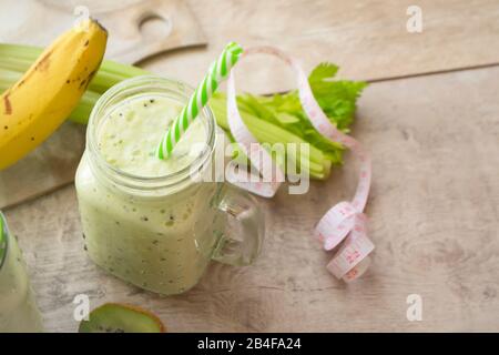 Gesunder Grünsaftkoktail oder Smoothie mit Messband. Glas mit Papierstroh. Gesundes Essen, Entgiften, Entsaften, Fasten, Körperreinigung Stockfoto