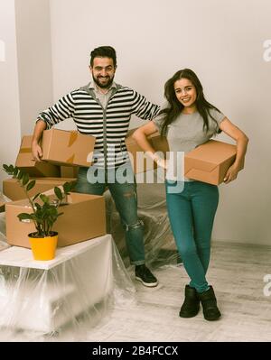 Aufgeregt, junges Paar beweglichen nach Hause stehen dicht beieinander mit Karton Kartons in ihren Händen. Stockfoto