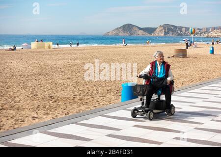 Benidorm, Spanien - 25. Februar 2020: Frau mit Mobilitätsroller im Levante Strandbereich in Benidorm, Spanien Stockfoto