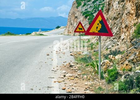 Typische Warnzeichen gegen Steinschläge und Rind auf einer Landstraße in Griechenland Stockfoto