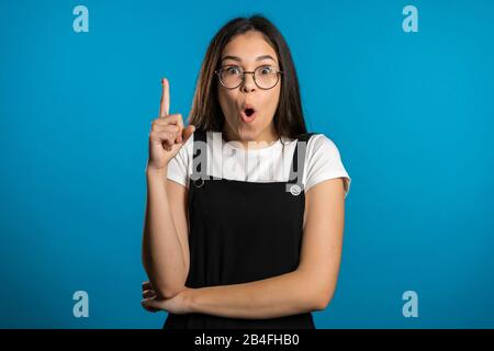 Porträt des asiatischen Denkens über Mädchen mit dem Ideenmoment, der mit dem Finger nach oben zeigt Stockfoto