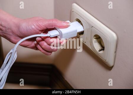 Close-up Frau die Hand Stecker in die Steckdose. Weibliche hand ausstecken Stockfoto