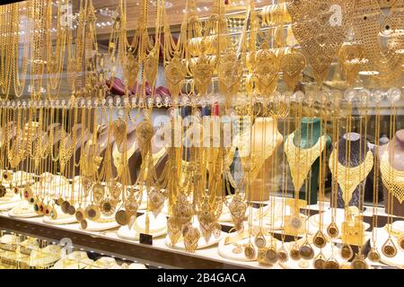 Goldene Halsketten und Armbänder, die auf verschiedene Weise vor dem Laden entworfen wurden. Stockfoto