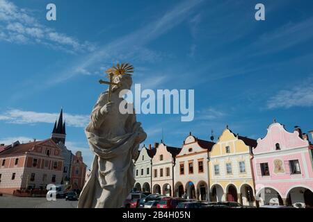 TelC, Tschechien - UNESCO-Weltkulturerbe. Eine Statue der Heiligen Margarethe aus der Zeit des Barock mit Bürgerhäusern über dem Torbogen der Renaissance Stockfoto