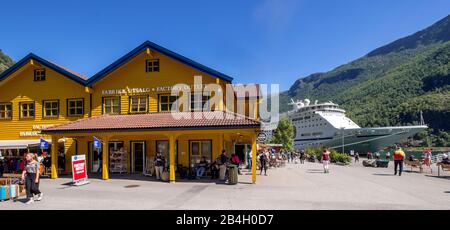 Touristen in Flåm, FACTORY KUTSALG FACTORY OUTLET, Geschäfte, gelbes Holzhaus, Ausflugsboot, Fjord, Berg, Bäume, blauer Himmel, Sogn og Fjordane, Norwegen, Skandinavien, Europa Stockfoto