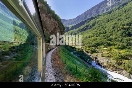 Reisen Sie mit Flambahn, Eisenbahreise, Blick von Flåmsbana, Ryavegen, Tunneleingang, Berge, Wälder, Wiesen, Fjord, blauer Himmel, Flåm, Sogn og Fjordane, Norwegen, Skandinavien, Europa Stockfoto