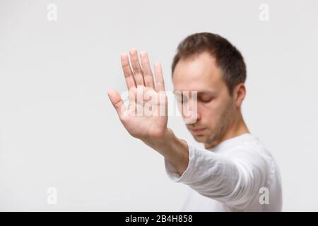 Die Nahaufnahme des wütenden Mannes verweigert das Angebot und zeigt eine Geste der Verweigerung von Junkfood, lehnt etwas unangenehmes, selektives Fokussieren ab. Negative Emotionen, Hand g Stockfoto