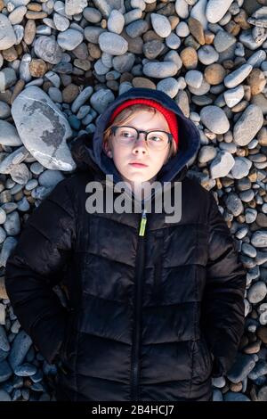 Draufsicht auf den Jungen zwischen den grauen und braunen Steinen Stockfoto