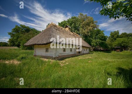 Altes ukrainisches Bauernhaus im Frühjahr mit Reetdach im alten Dorf der nationalen Architektur, Ukraine. Nationalmuseum Pirogovo in t Stockfoto