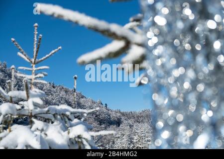 Schneebedecke Tannen im Wald mit silberner Lametta Dekorierung vor blauem Himmel in den Vogesen, Frankreich Stockfoto