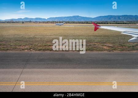 Blick aus dem Fenster eines Flugzeugs auf die Landebahn von Palma de Mallorca mit Bergkette, Charterflugzeug Stockfoto