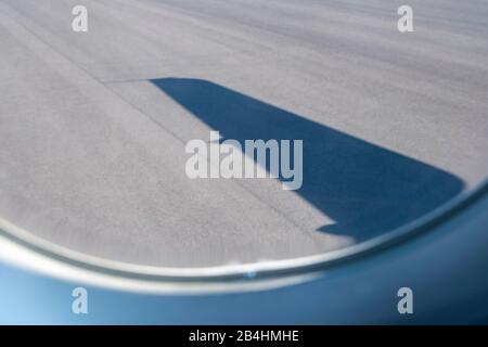 Blick vom Flugzeugfenster auf die Landebahn mit Schatten des Flügels Stockfoto