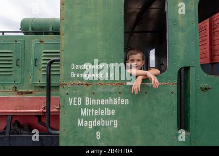 Deutschland, Sachsen-Anhalt, Magdeburg, Junge angelehnt an das Fenster einer alten Lok, DDR, Handelshafen Magdeburg. Stockfoto