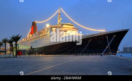 Beleuchtete Hotel- und Museumsschiff Queen Elizabeth 2 (QE2) am Pier in der Dämmerung, Dubai, Persischer Golf, Vereinigte Arabische Emirate Stockfoto