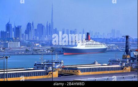 Hotel- und Museumsschiff Queen Elizabeth 2 (QE2) im Hafen mit Stadtsilhouette und Burj Khalifa 828m, Dubai, Persischer Golf, Vereinigte Arabische Emirate Stockfoto