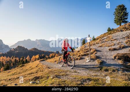 Ein Mann fährt auf den Gleisen im Tal von San Nicolò, Fassa, Trentino, in den Bergen, in Italien mit einem Fahrrad MTB Stockfoto